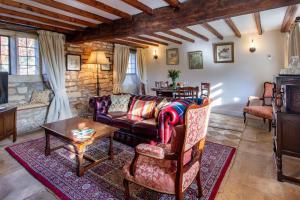 a living room with a couch and a table at Graziers Cottage - character Cotswold cottage with inglenook, parking and pub nearby in Cheltenham