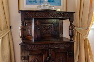 an old wooden cabinet in a room with curtains at Graziers Cottage - character Cotswold cottage with inglenook, parking and pub nearby in Cheltenham