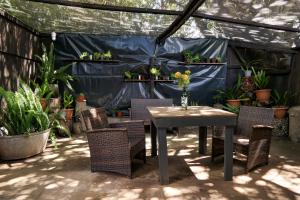 a patio with a table and chairs and potted plants at Canary Cottage in Greyton