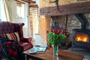 a living room with a fireplace and a vase of flowers on a table at Graziers Cottage - character Cotswold cottage with inglenook, parking and pub nearby in Cheltenham