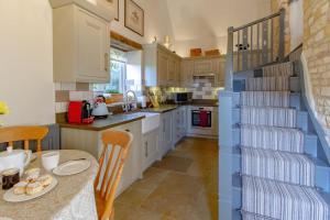 a kitchen with a table and a blue staircase at Graziers Cottage - character Cotswold cottage with inglenook, parking and pub nearby in Cheltenham +29 photos
