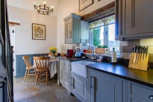 a kitchen with blue cabinets and a counter top at Graziers Cottage - character Cotswold cottage with inglenook, parking and pub nearby in Cheltenham