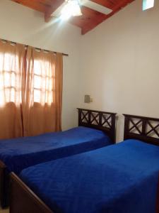 a bedroom with two beds with blue sheets and a window at Alquiler temporario Santo Tome in Santo Tomé