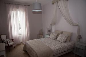 ein weißes Schlafzimmer mit einem Bett und einem Fenster in der Unterkunft bel appartement en pierre de 88 M2 charme d’antan in Margaux