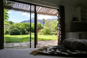 a bedroom with a bed and a large glass window at Canary Cottage in Greyton