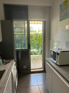 uma cozinha com um micro-ondas e uma porta para um pátio em Bel appartement proche de la mer em Nice