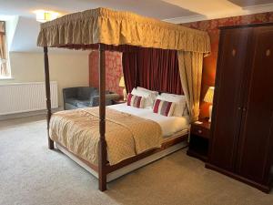 a bedroom with a canopy bed and a chair at East Ayton Lodge Hotel, Scarborough in Scarborough