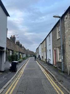 an empty street with buildings and a person walking down the street at Trinity, Central Cambridge Flat in Cambridge