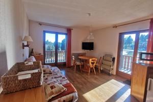 a living room with a couch and a table and windows at Appartement 4 personnes au pied des pistes in Les Déserts