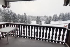 einen Balkon mit einer Bank und schneebedeckten Bäumen in der Unterkunft Appartement 4 personnes au pied des pistes in Les Déserts