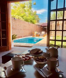 una mesa con comida y tazas en una mesa con piscina en Alquiler temporario Santo Tome, en Santo Tomé