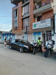 un oficial de policía parado junto a un coche y una motocicleta en Confort Putumayo, en Mocoa