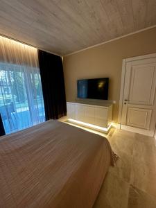 a bedroom with a bed and a flat screen tv at Park-Hotel Tihiy Les in Prokhorovka