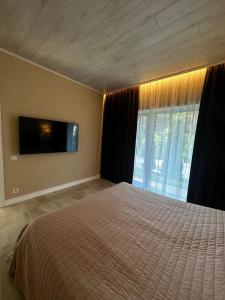 1 dormitorio con 1 cama y TV de pantalla plana en Park-Hotel Tihiy Les en Prokhorovka