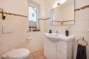een witte badkamer met een wastafel en een toilet bij Ferienhaus Sunshine in Korswandt +10 foto's