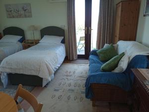 a bedroom with two beds and a couch at Cowslip Corner Room with Sea View in Broad Haven