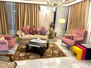 a living room with pink furniture and a chandelier at Luxury Apartment 2 Nasr City- City stars in Cairo