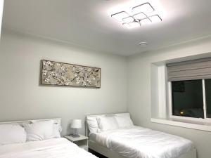 Un dormitorio con 2 camas y una ventana con una foto en la pared. en Modern and New house near PNE, en Vancouver