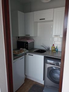 una pequeña cocina con armarios blancos y microondas en Cowslip Corner Room with Sea View en Broad Haven
