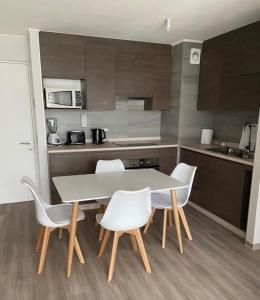 una cocina con mesa y sillas blancas. en Departamento Full Concepcion, en Concepción