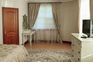 a bedroom with a bed and a desk and a window at Hotel Miss Mari in Karagandy