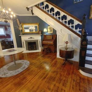 een woonkamer met een trap en een piano bij Historic Escape in Mansion Row - Sleeps 12! in New Albany