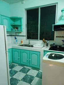 eine Küche mit blauen Schränken, einem Waschbecken und einem Fenster in der Unterkunft Résidence Lennards 2 in Grand Baie