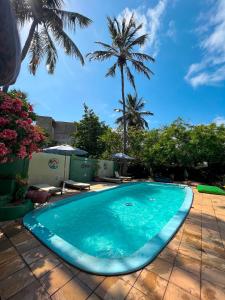 una piscina azul con palmeras en el fondo en Free! Hostel Vila, en Pipa