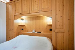 1 dormitorio con armarios de madera y 1 cama blanca en Emma Home en Mezzolombardo