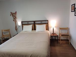 1 Schlafzimmer mit einem großen weißen Bett mit 2 Stühlen in der Unterkunft Oficina do Joe , Bungalow Gitte in Outeiro