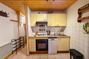 a small kitchen with yellow cabinets and a stove at Spacieux appartement au centre de la station in Les Déserts
