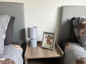 a table with a picture and a lamp next to two beds at The Heilan' Coo Apartment in Helensburgh