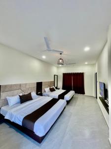 a bedroom with two beds and a television in it at Tekri Farms and Retreat in Ujjain