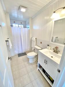 a white bathroom with a toilet and a sink at Eleuthera Retreat - Villa & Cottages on pink sand beachfront in North Palmetto Point