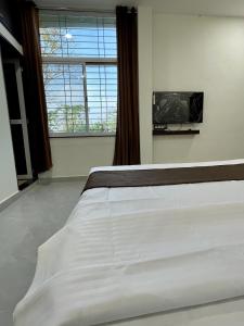 um quarto com uma grande cama branca e uma janela em Tekri Farms and Retreat em Ujjain