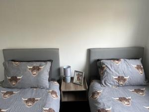 a bedroom with two beds with pillows with cows on them at The Heilan' Coo Apartment in Helensburgh