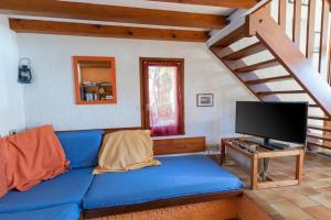 uma sala de estar com um sofá azul e uma televisão em Bastidon Avec Terrasse Vue Mer em Carqueiranne
