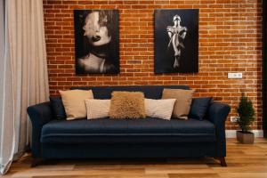 a blue couch in front of a brick wall with three pictures at K&J Loft in Tbilisi City