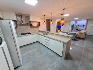 a kitchen with a refrigerator and a living room at Casa Luxo Vista Incrível Meaípe in Guarapari