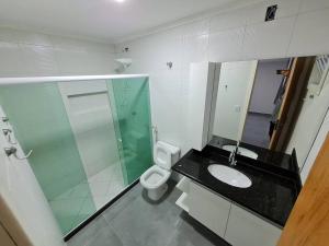 a bathroom with a sink and a toilet and a mirror at Frente Mar Vista Incrível Meaípe in Guarapari
