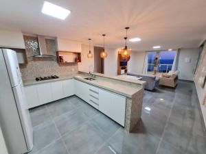 a kitchen with a counter top and a living room at Frente Mar Vista Incrível Meaípe in Guarapari