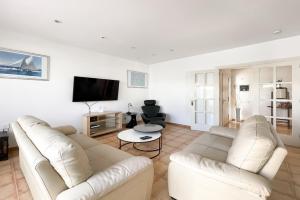 sala de estar con 2 sofás blancos y TV de pantalla plana en Villa Emilia by Best Holidays Fuerteventura en Corralejo