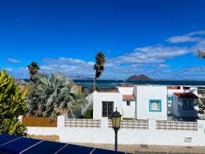 a white house with a palm tree and the ocean at Villa Emilia by Best Holidays Fuerteventura in Corralejo
