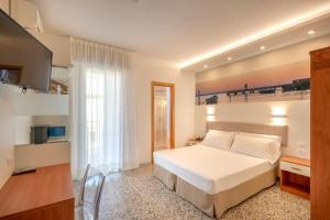 - une chambre avec un lit blanc et une télévision dans l'établissement Hotel Atenea Golden Star, à Caorle