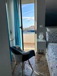 a bedroom with a chair and a view of the beach at Ortigia D'aMare Apartment in Siracusa