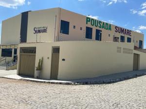 a building on a street next to a brick road at Pousada Sumaré in Caruaru