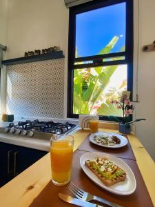 a table with a plate of pizza and two glasses of orange juice at Tiny House By The Beach in Mazatlán