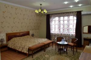 a bedroom with a bed and a table and a window at Hotel Miss Mari in Karagandy