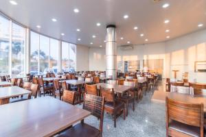 a restaurant with tables and chairs and windows at Foz Budget Hotel in Foz do Iguaçu