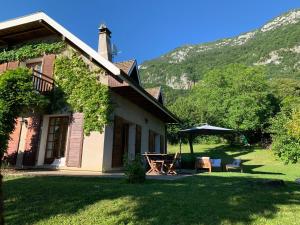 ヴェリエ・デュ・ラックにあるMaison avec Piscine LAC d'ANNECY - proximité Plage VEYRIER DU LACの庭のテーブルと傘を持つ家